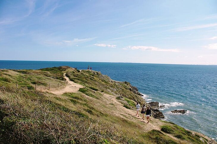 Sentiers du littoral, randonnées incontournables dans le Morbihan Randonneurs sur un sentier du littoral du Morbihan, chemin côtier offrant une vue sur l’océan pour savoir que faire dans le Morbihan.