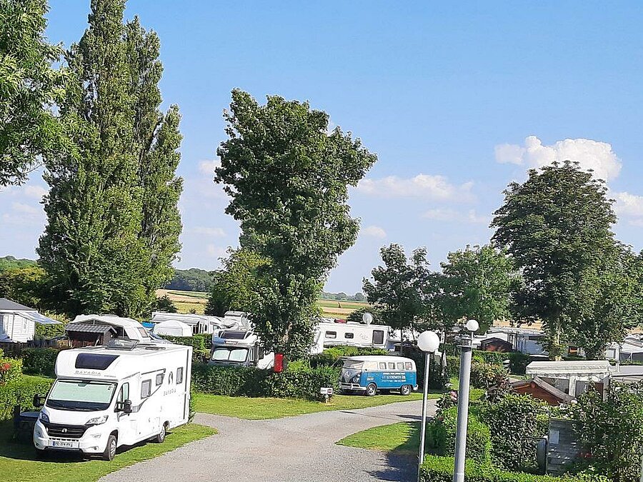 Emplacements spacieux pour camping-cars et vans entourés de verdure dans un camping en Picardie, offrant calme et confort pour des vacances proches de la nature.