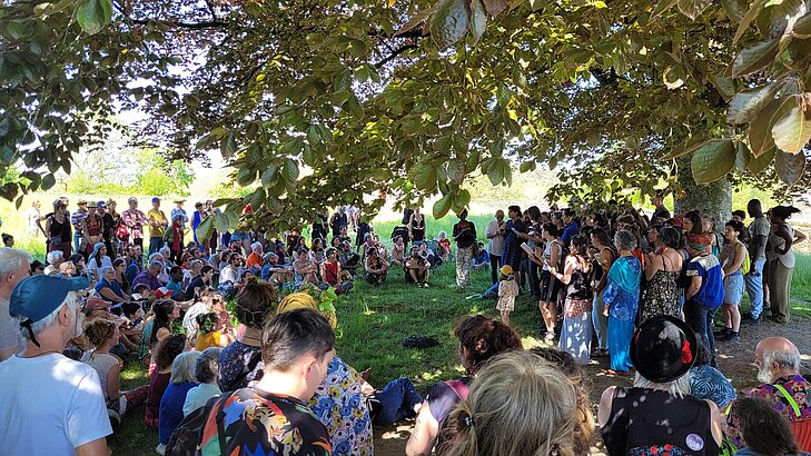 Public rassemblé sous les arbres pour un concert du festival « À Travers Chants » à Rochefort-en-Terre, un événement incontournable pour vivre le village autrement.