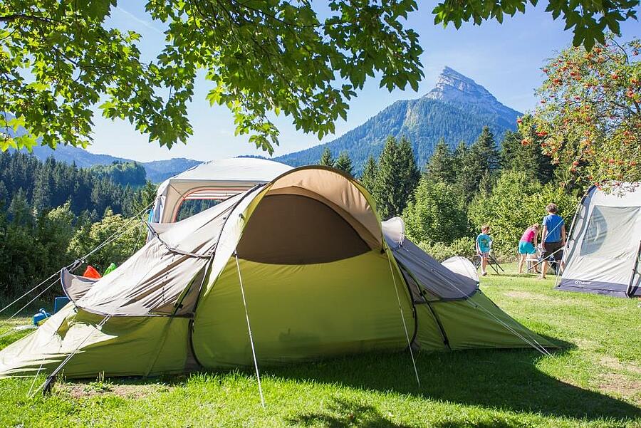 Emplacement de camping avec tente au pied des montagnes en Isère, offrant un cadre naturel et préservé, idéal pour des vacances en plein air en famille.