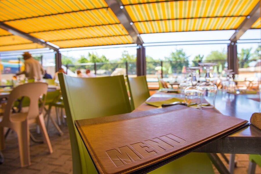 Terrasse ombragée d’un restaurant de camping près d’Annecy, parfaite pour des repas conviviaux en famille ou entre amis.