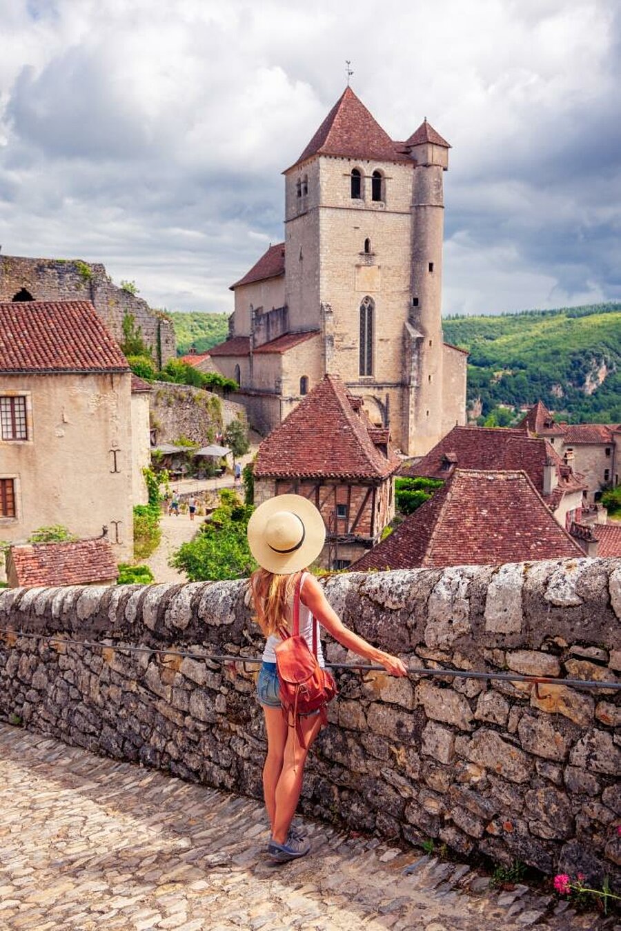 Voyageuse admirant Saint-Cirq-Lapopie et son église dans le Lot lors d’un séjour en camping en Occitanie.
