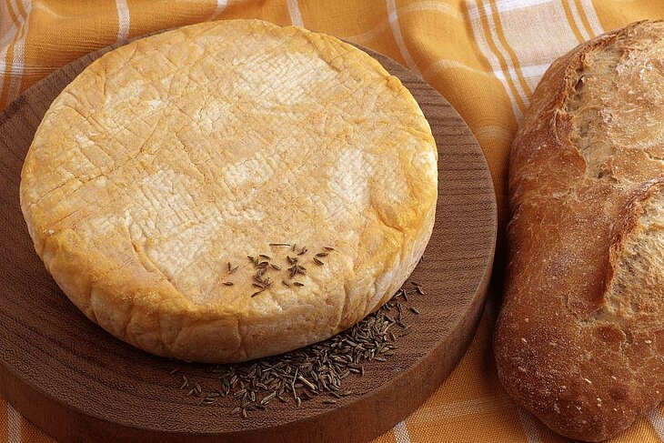 Munster fermier accompagné de pain, symbole des traditions et du savoir-faire artisanal dans les Vosges.