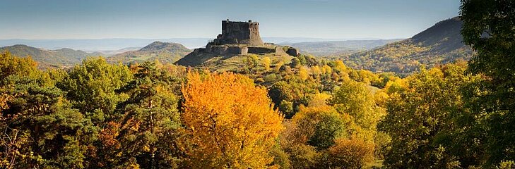 Les paysages d’Auvergne en automne Château dominant des collines boisées aux couleurs d’automne en Auvergne