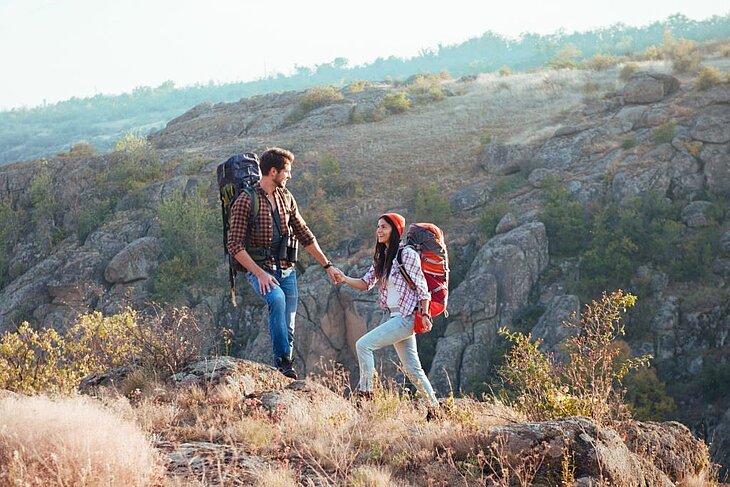 Couple en randonnée en montagne, sacs à dos et paysages naturels, partageant un moment de déconnexion lors d’un séjour à deux.