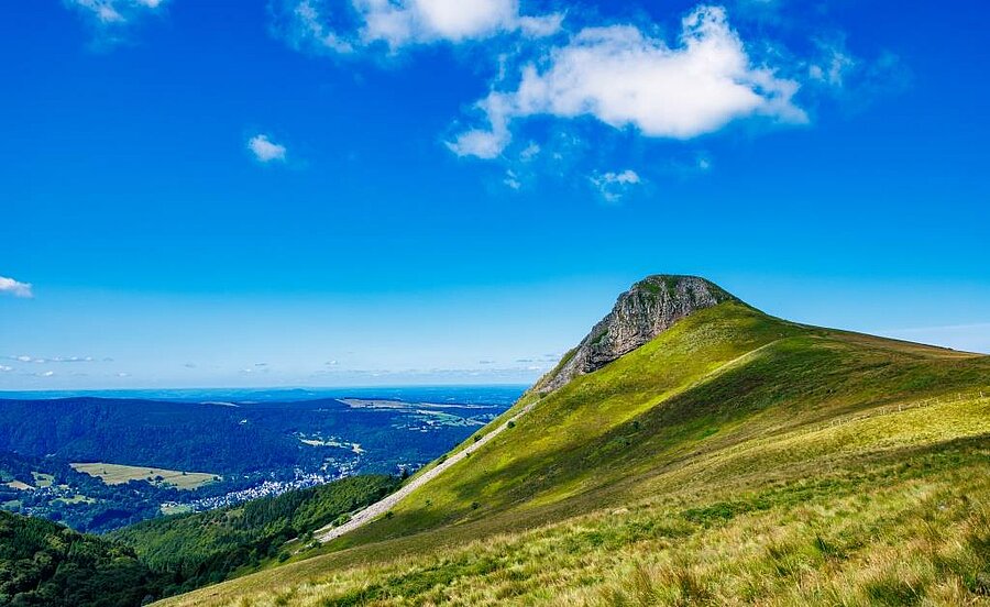 Paysage volcanique d’Auvergne avec sommet verdoyant et vue dégagée sur la vallée