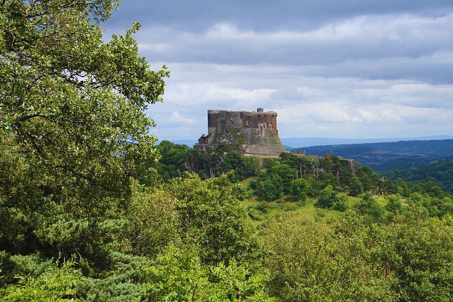 Vue aérienne du château de Murol dominant la vallée, entouré de forêts et de villages typiques d’Auvergne.