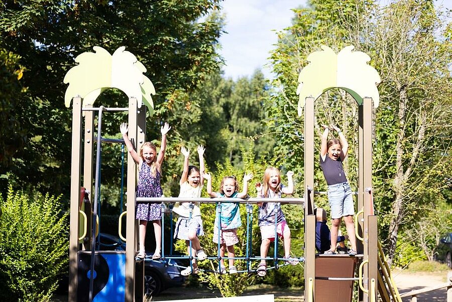 Enfants s’amusant sur une aire de jeux dans un cadre naturel au sein d’un camping en Bretagne, idéal pour des vacances familiales conviviales et mémorables.