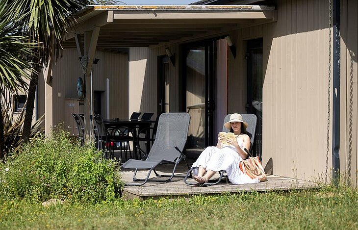 Profiter du calme pendant les ponts de mai Personne se détendant sur la terrasse d’un hébergement en camping, profitant du calme pendant les ponts de mai