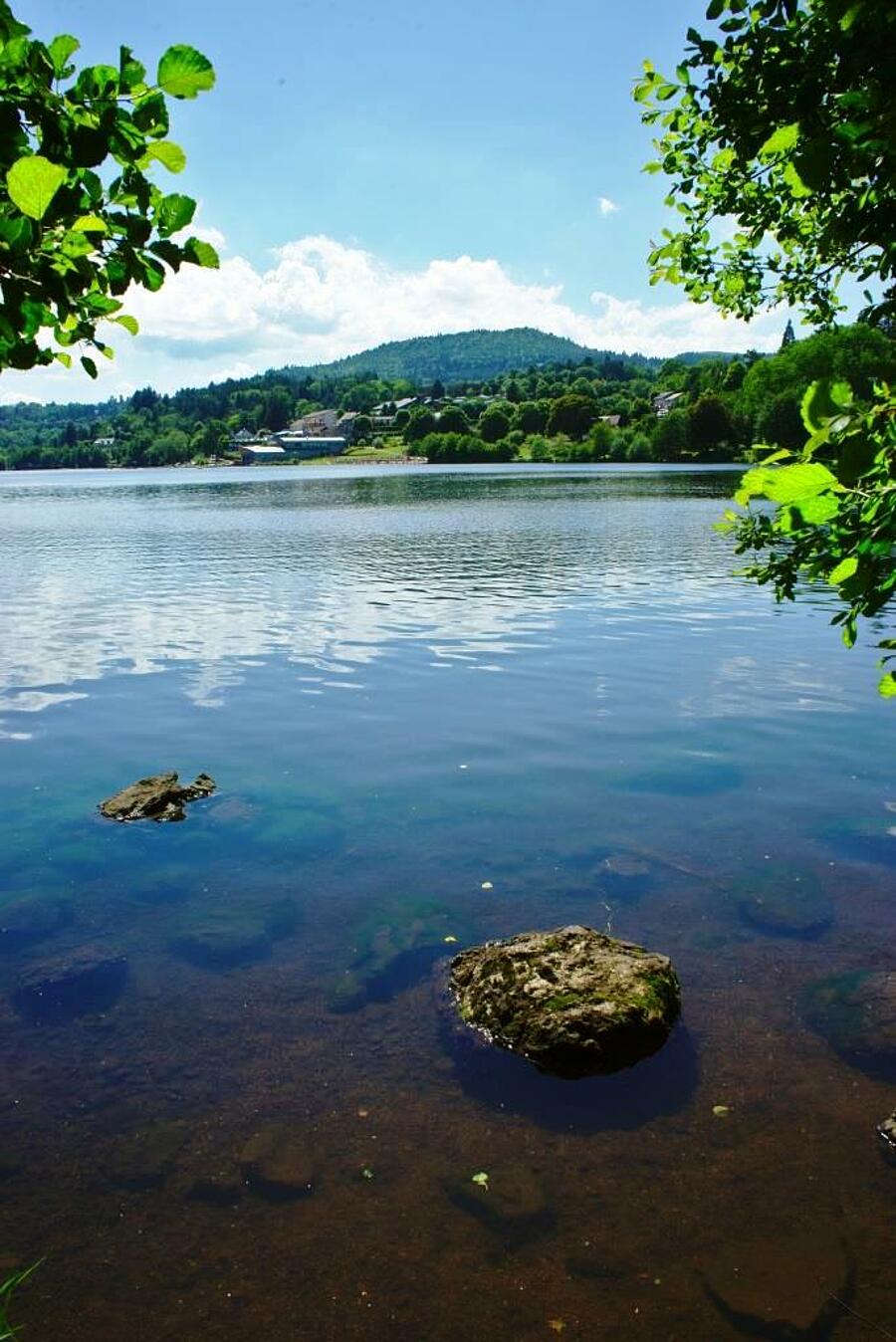 Vue apaisante du lac cristallin Aydat entouré de verdure dans le Puy-de-Dôme, parfait pour des vacances en camping au cœur des volcans d’Auvergne.
