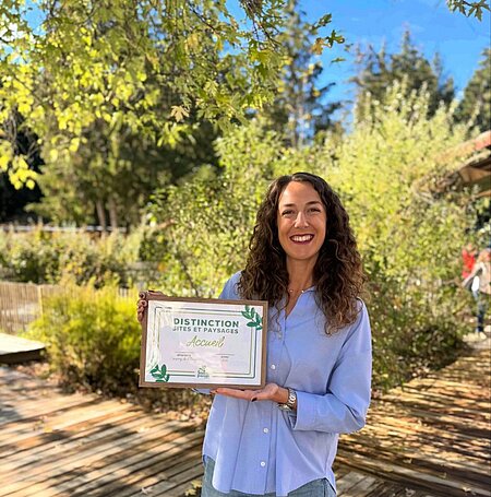 Carla, directrice du camping Sites et Paysages L’Étang à Brissac-Quincé, présente la distinction Accueil décernée par le réseau pour ses excellentes notes de satisfaction client.