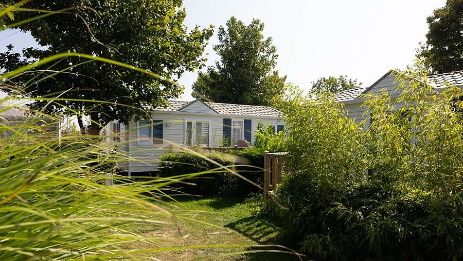 Mobil-home moderne entouré de verdure dans un camping en Côte d'Opale, idéal pour des vacances confortables en famille.