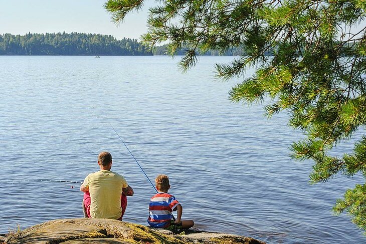 Père et fils pêchant au bord d’un lac dans les Vosges, une activité de plein air idéale à partager en famille.