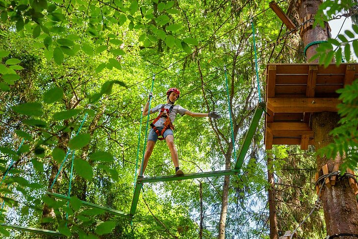 Jeune fille sur un parcours d’accrobranche au cœur de la forêt à Oasis Aventura, une activité ludique et sportive idéale pour les familles en séjour autour d’Eclassan.