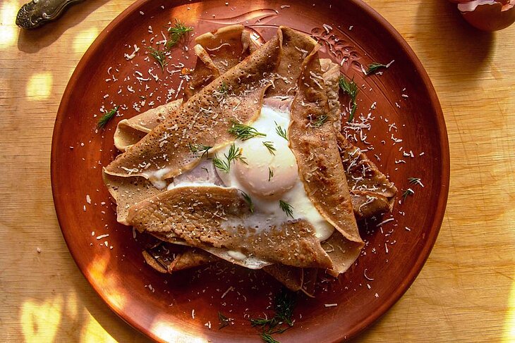 Galette bretonne traditionnelle Galette bretonne garnie servie dans une assiette, spécialité culinaire à déguster lors d’un séjour gourmand, idée savoureuse quand on se demande que faire en Bretagne.