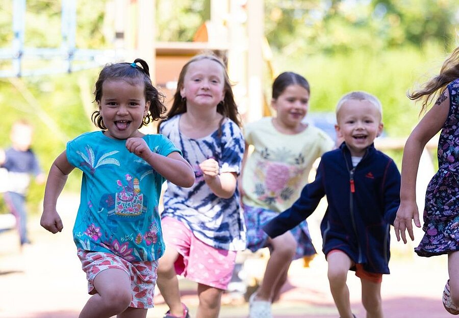 Groupe d’enfants courant et s’amusant dans une aire de jeux d’un camping Sites et Paysages, une escapade joyeuse pour le week-end de l’Ascension.