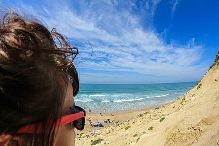 Gros plan d'une femme admirant la vue sur la mer, évoquant une évasion estivale.