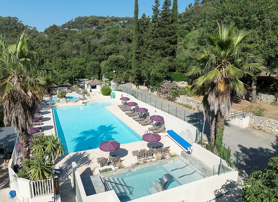 Piscine entourée de transats et palmiers dans un camping de la Côte d’Azur, cadre idéal pour des vacances en famille