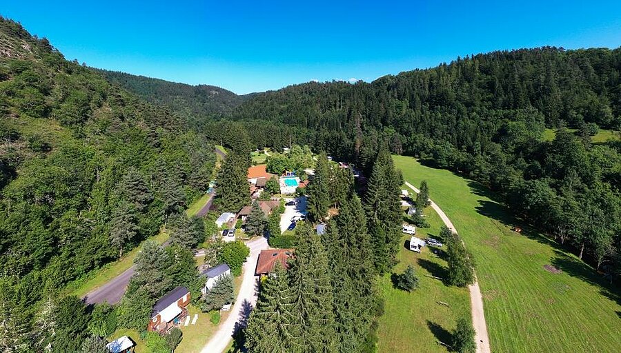 Vue aérienne d’un camping 4 étoiles entouré de nature près du Puy en Velay, idéal pour les familles