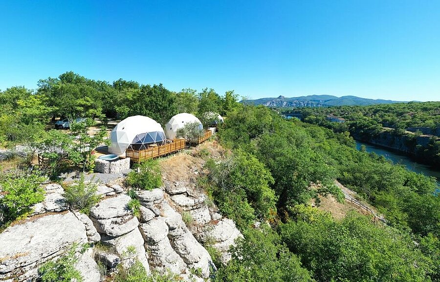 Terrasse en bois avec jacuzzi privatif et transats au camping près de Balazuc, vue panoramique sur les gorges et la nature ardéchoise.