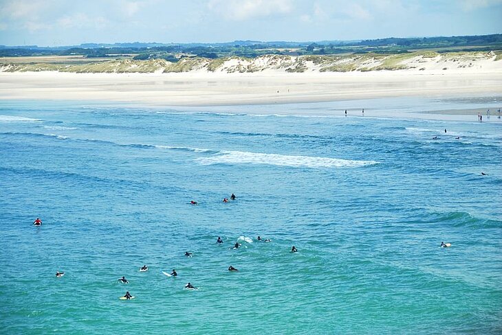 Surfeurs à la Pointe de la Torche à Plomeur, l’un des spots les plus réputés de Bretagne pour les amateurs de glisse et de tourisme sportif en plein air.