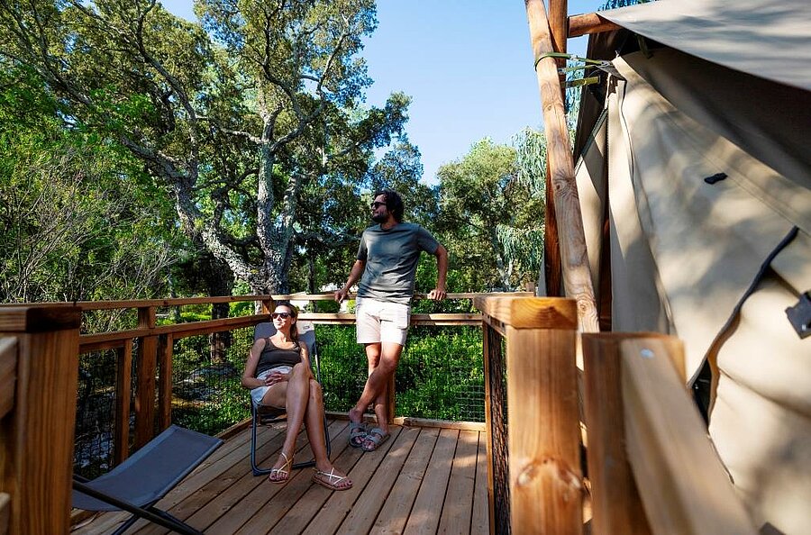 Couple profitant d’un moment de détente sur la terrasse d’un hébergement de camping en couple, entouré par la nature
