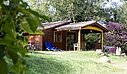 Chalet en bois dans un camping, entouré de verdure, offrant un hébergement confortable pour des vacances en pleine nature.