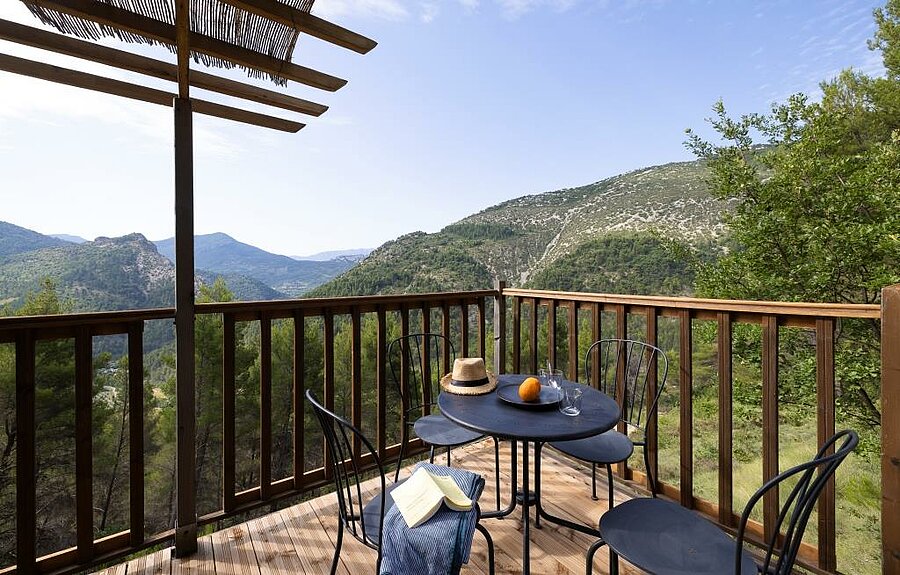 Terrasse en bois d’un hébergement de camping dans la Drôme avec vue panoramique sur les reliefs verdoyants