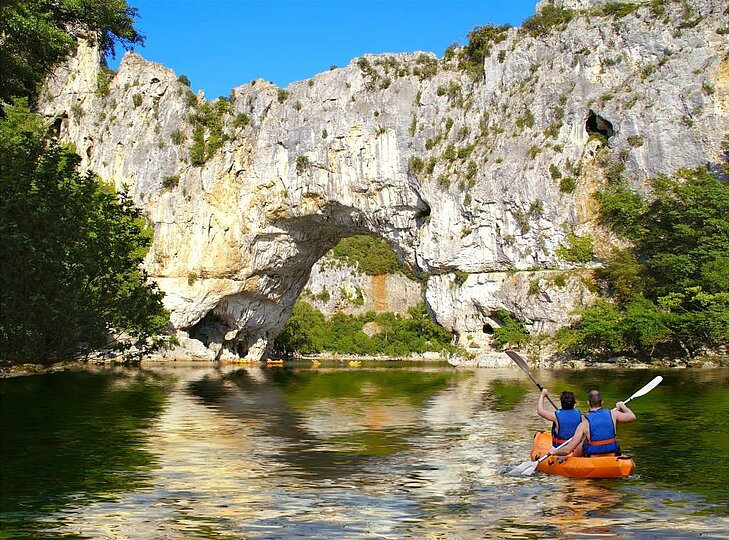 Descente en canoë sous le Pont d'Arc en Ardèche, un site emblématique d’Auvergne-Rhône-Alpes, idéal pour les amateurs de sports d’eau vive et de paysages spectaculaires.