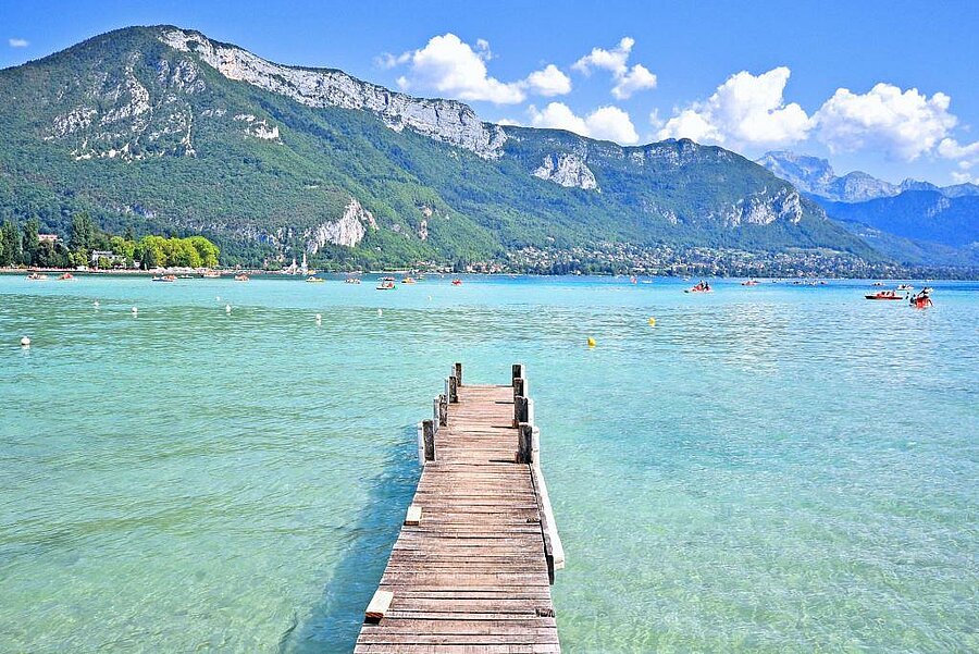 Ponton en bois sur le lac d’Annecy, eau turquoise et montagnes en toile de fond