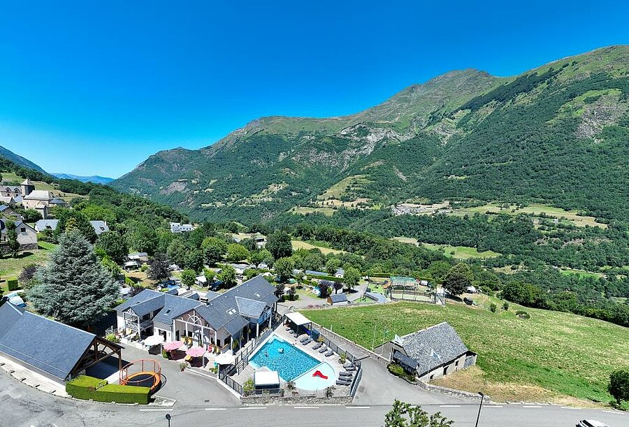 Vue aérienne du camping Pyrénévasion à Sazos près de Lourdes, avec piscine chauffée et panorama sur les montagnes verdoyantes.