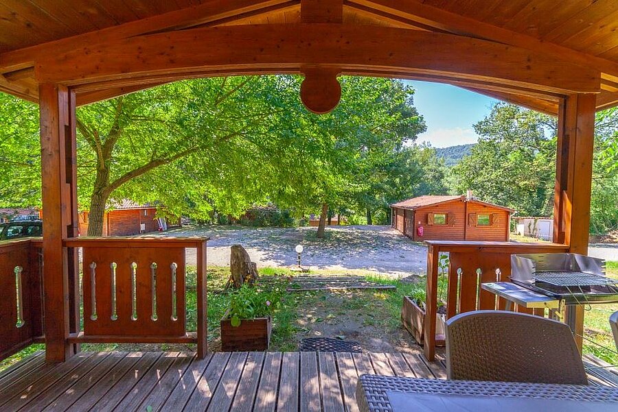 Vue depuis la terrasse d’un chalet en bois dans un camping Sites et Paysages, parfait pour un séjour détente lors du pont de mai.