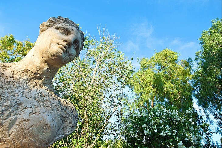 Sculpture antique de femme au regard penché, entourée de verdure et de ciel bleu à Martres-Tolosane