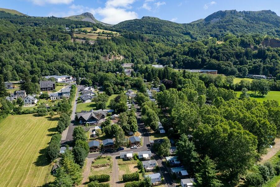 Vue aérienne d’un camping niché au cœur des paysages verdoyants du Puy-de-Dôme, idéal pour des vacances nature en Auvergne.