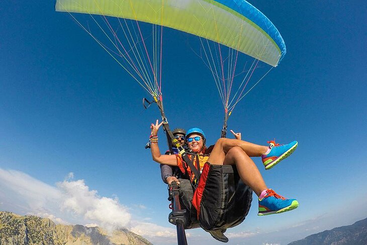 Personne en parapente biplace survolant les montagnes ardéchoises, pour une activité à sensations autour de Joannas.