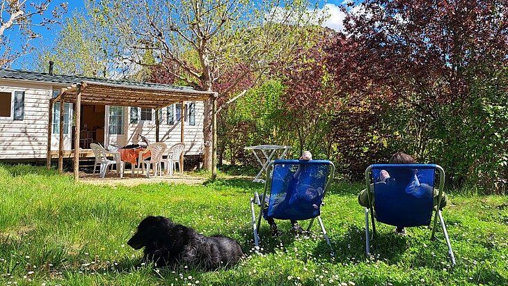 Séjour au calme au Domaine de l’Écluse dans la Drôme Vacanciers et leur chien se reposant devant un mobil-home avec terrasse au Domaine de l’Écluse, dans la Drôme.