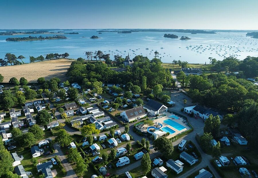 Vue aérienne d’un camping 4 étoiles avec piscine près du littoral et des îles en France.