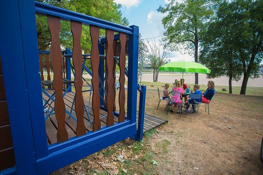 Famille prenant le petit-déjeuner en plein air devant une roulotte colorée dans un camping près de la Sologne, avec vue sur la Loire.