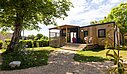 Mobil-home en bois avec terrasse ombragée et climatisation, idéal pour des vacances au frais en camping nature.