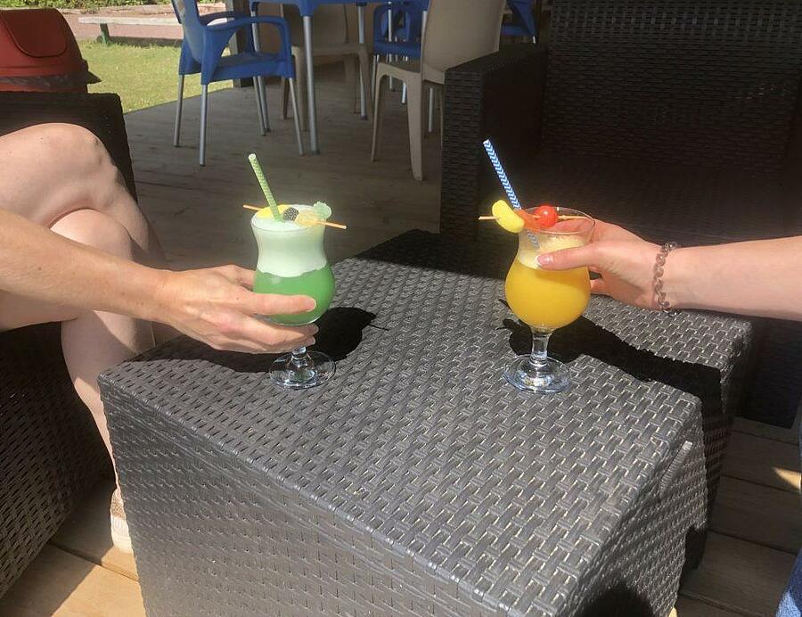 Deux verres de cocktails colorés posés sur une table en résine tressée au Camping de la Baie en baie de Somme.