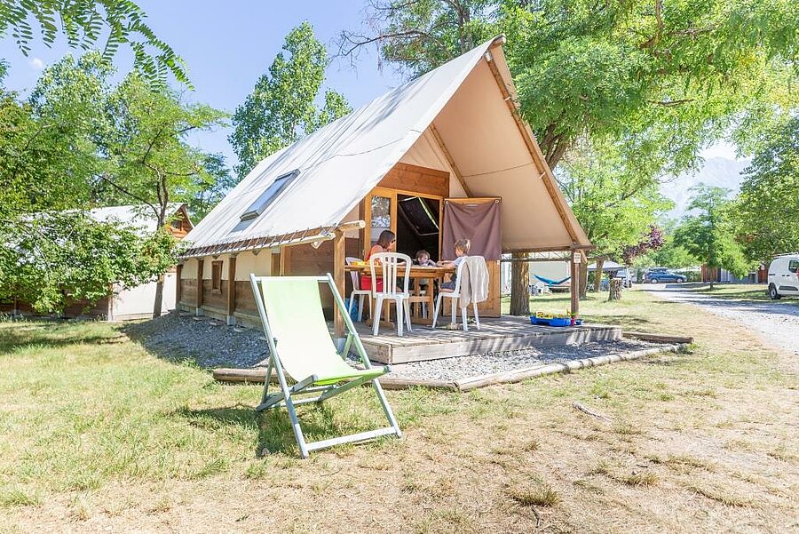Tente lodge avec terrasse dans un camping près d’Embrun, hébergement nature idéal pour des vacances en famille dans les Hautes-Alpes.