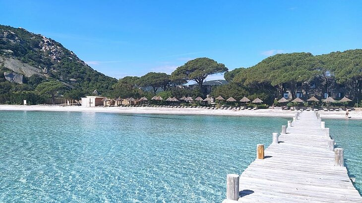 Plage de Santa Giulia en Corse du Sud, eau turquoise peu profonde, sable blanc et ponton en bois, idéale pour la baignade.