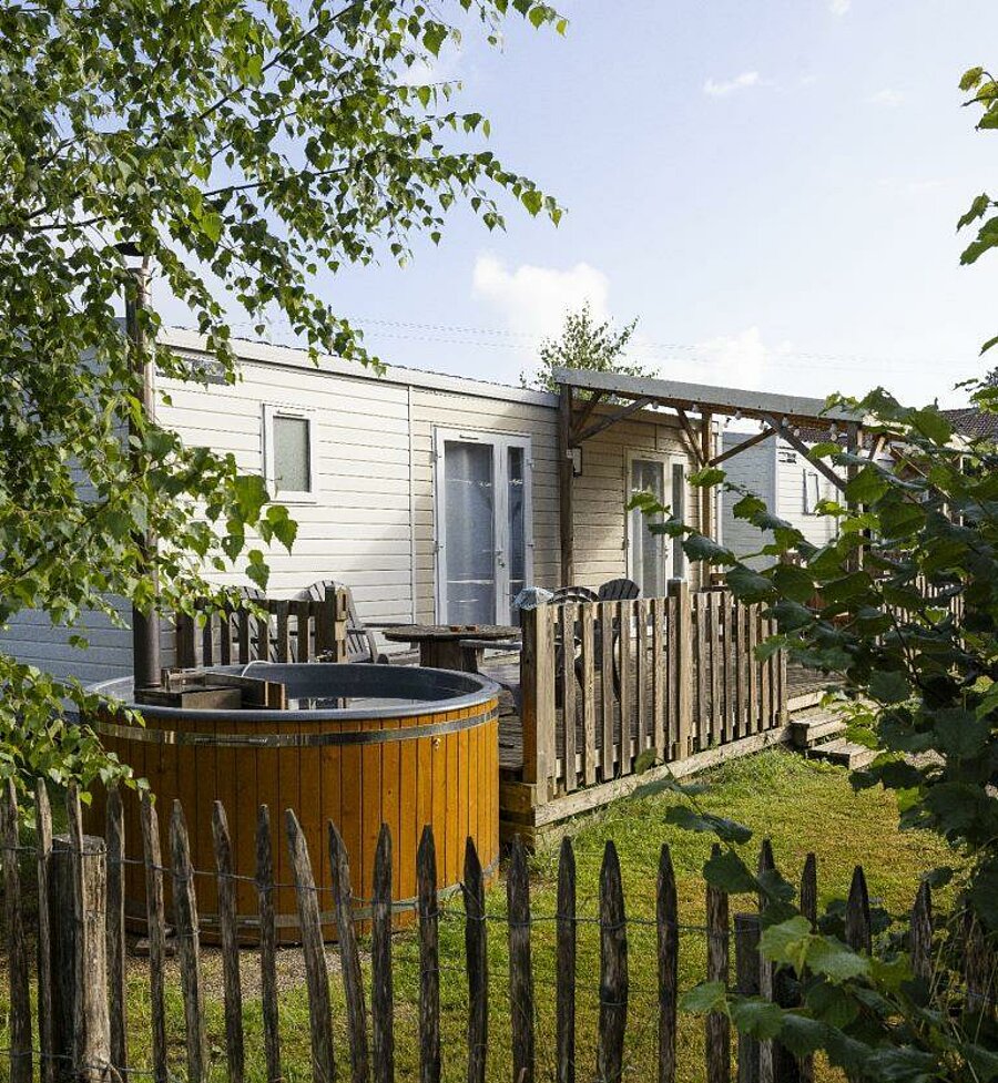 Mobil-home avec terrasse et bain nordique en bois dans un camping près de Gérardmer, idéal pour un séjour détente dans les Vosges.