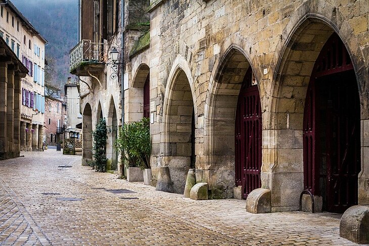 Centre historique de Saint-Antonin-Noble-Val Ruelle pavée du centre historique de Saint-Antonin-Noble-Val bordée de maisons anciennes et d’arcades en pierre.