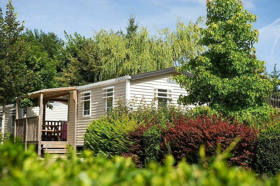Mobil-home confortable entouré de verdure dans un camping du Jura, idéal pour une location en pleine nature