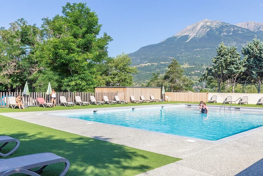 Piscine d’un camping près du lac de Serre-Ponçon, avec vue sur les montagnes environnantes.