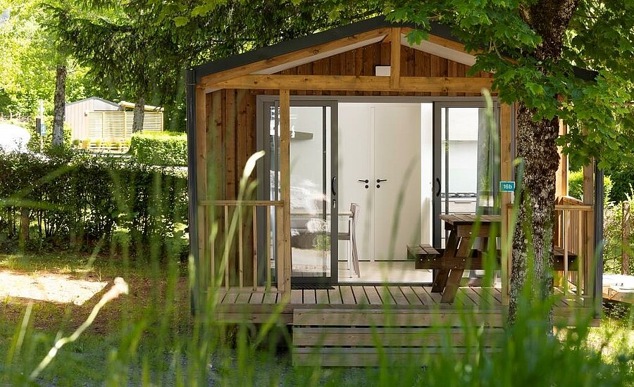 Chalet en bois niché sous les arbres, parfait pour des vacances nature et confort en camping à Murol.