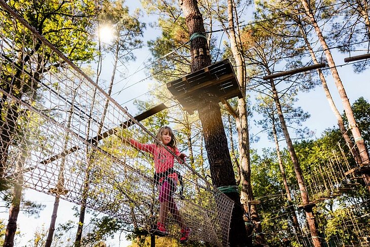 Enfant sur un parcours accrobranche en forêt, activité de loisirs familiale au cœur du tourisme en Nouvelle-Aquitaine.
