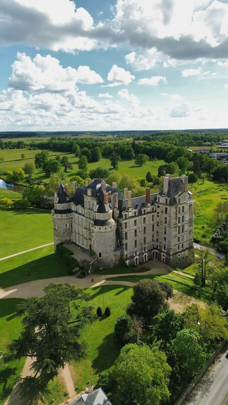 Vue aérienne du Château de Brissac entouré de verdure, un incontournable à visiter lors d’un séjour en camping dans le Maine-et-Loire, au cœur du Val de Loire.