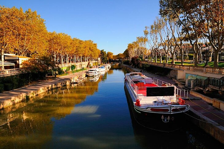 Balade le long du canal de la Robine à Narbonne Péniche amarrée le long d’un canal bordé d’arbres aux couleurs d’automne à Narbonne